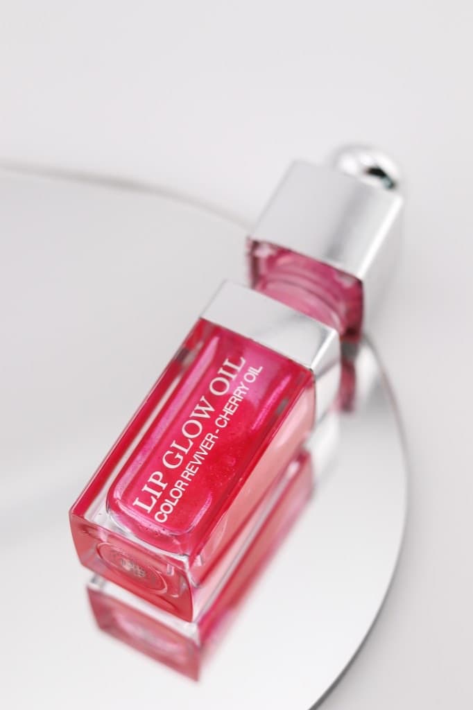 Packshot premium d'une huile à lèvres rose sur miroir